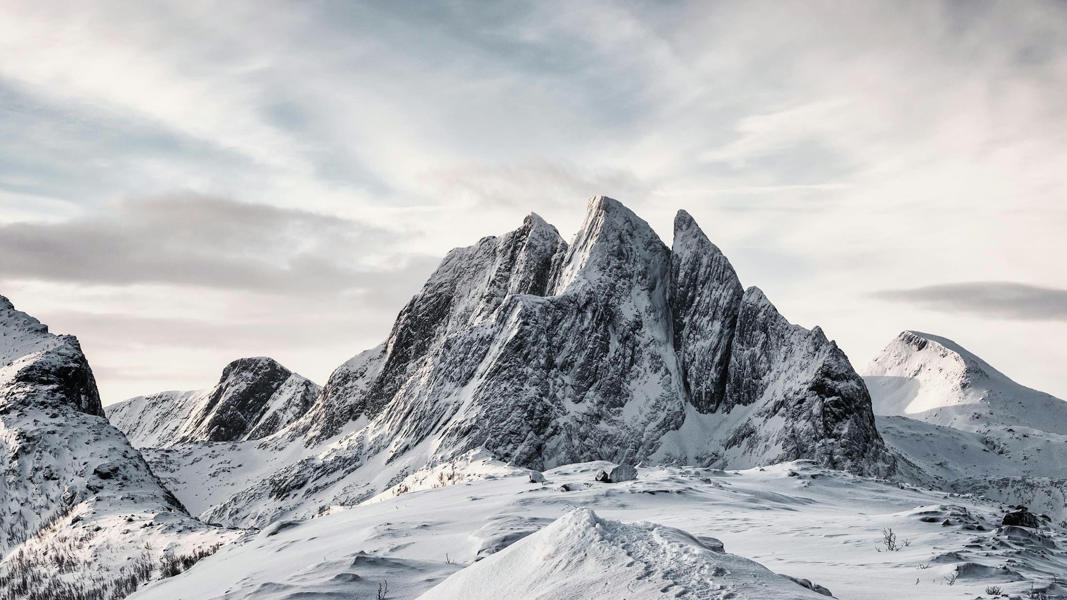 Snow-covered Norwegian mountain range under a pale winter sky